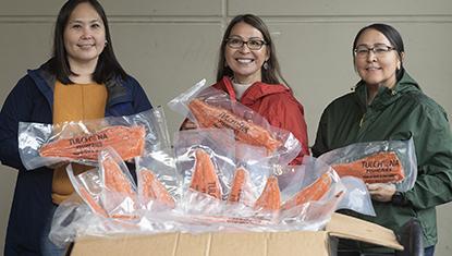 Three BBNC employees holding packaged salmon